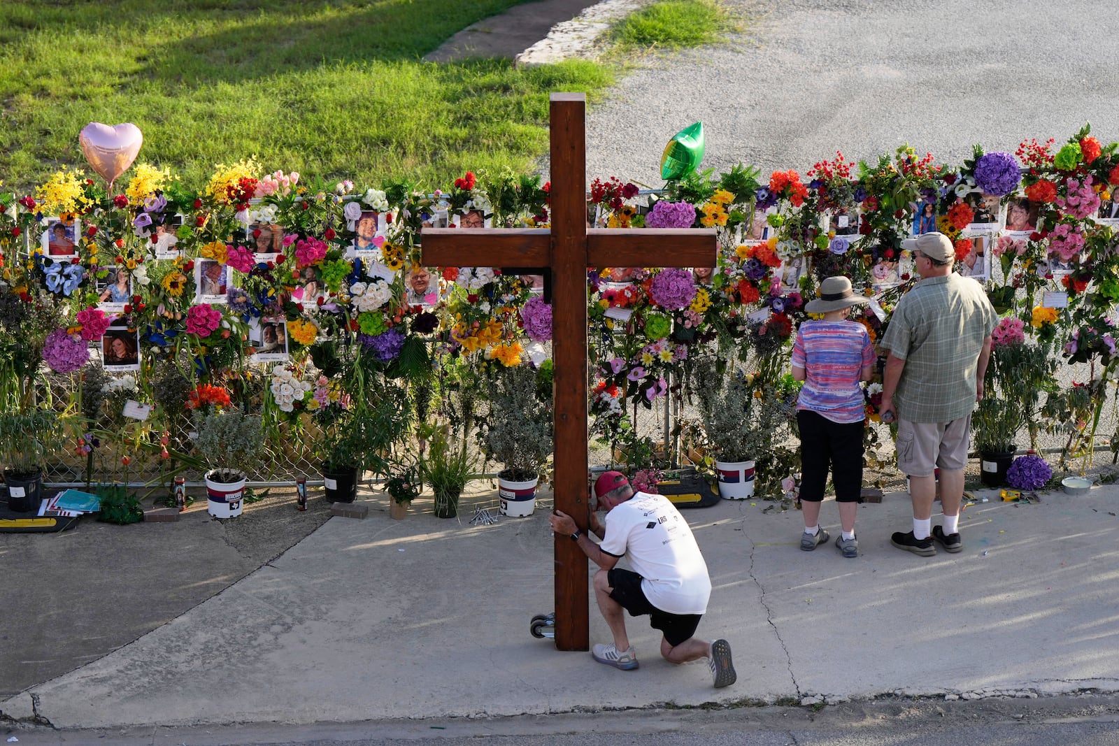 Dan Beazley, of Mich., prays with a large cross at a memorial for flood victims on Thursday, July 10, 2025, in Kerrville, Texas. (AP Photo/Ashley Landis)