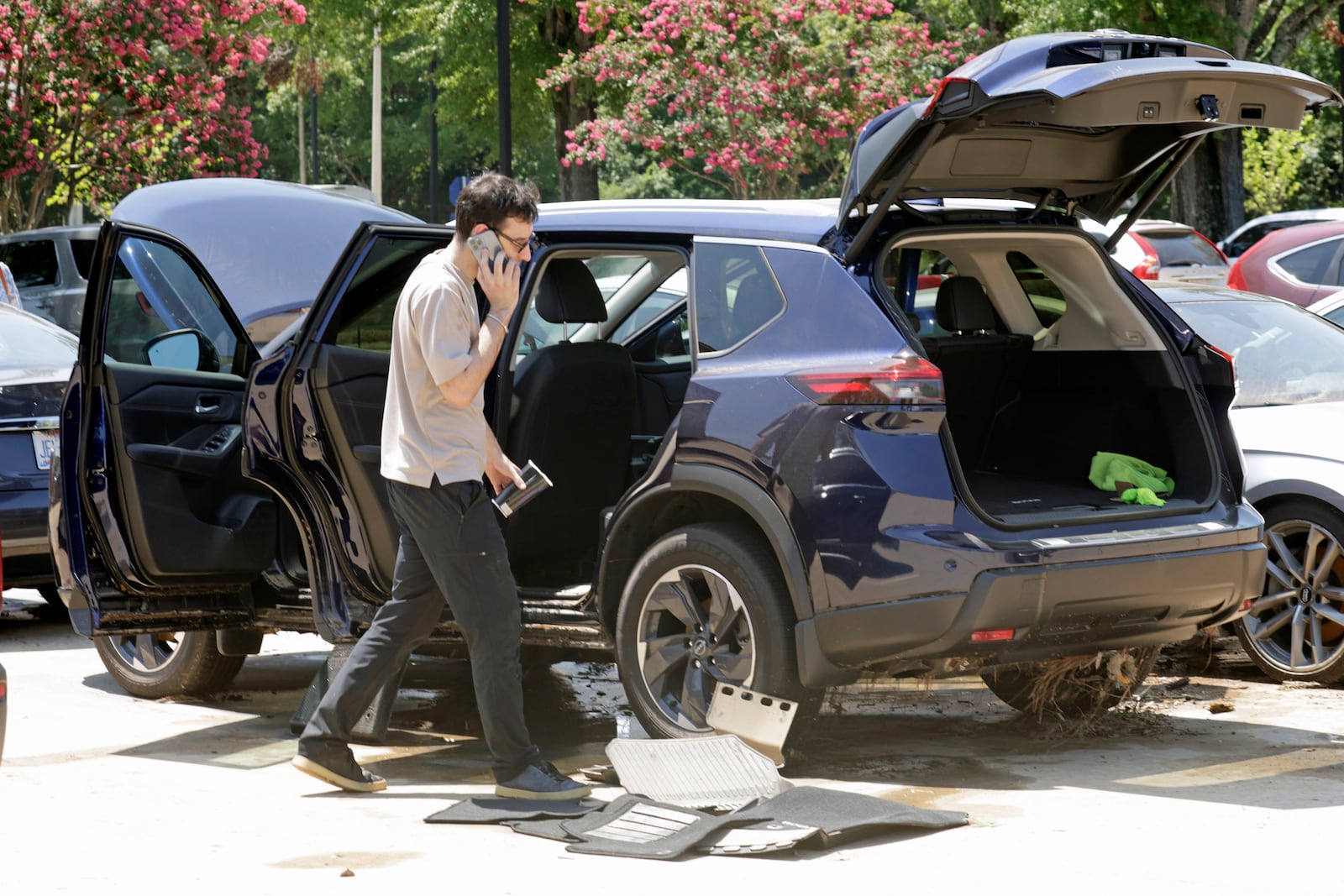 A man tries to dry his car out in a parking lot at University Place shopping center after it was flooded out during tropical storm Chantal, Monday, July 7, 2025, in Chapel Hill, N.C. (AP Photo/Chris Seward)