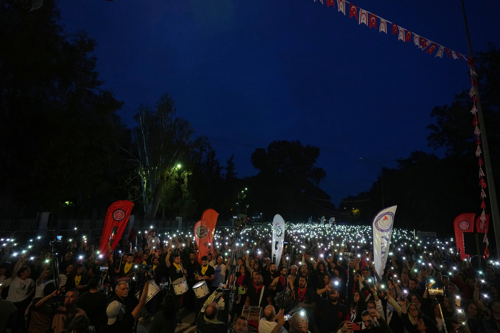 Turkish Cypriot protesters hold the lighted mobile phones aloft as they gather to protest against what they say is Turkey's attempt to erode their secular roots and to strengthen the hold of political Islam over their society, in the northern half of ethnically divided Cyprus' capital Nicosia, on Friday, May 2, 2025. (AP Photo/Petros Karadjias)