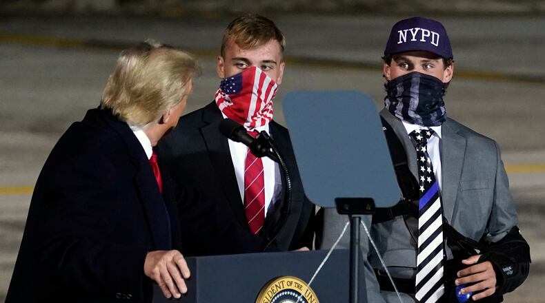 President Donald Trump brings two football players from Little Miami High School who were suspended for a short time for carrying flags that showed support for law enforcement at the start of a game on Sept. 11, onto stage as he speaks during a campaign rally at Eugene F. Kranz Toledo Express Airport, Monday, Sept. 21, 2020, in Swanton, Ohio. (AP Photo/Alex Brandon)