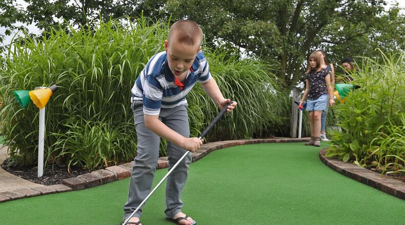 Mikey Harris, a camper with the Salvation Army’s Camp for Children with Disabilities, chases the ball around the green as he gets closer and closer to the hole during the camp’s weekly outing to Udders and Pudders at Young’s Jersey Dairy a few years ago. BILL LACKEY/STAFF