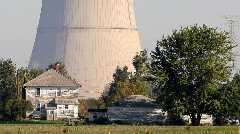 FILE-In this Oct. 5, 2011 file photo, the cooling tower of the Davis-Besse Nuclear Power Station looms over an adjacent farm in Oak Harbor, Ohio. Across the nation, a handful of nuclear plants unable to compete with natural gas and renewable energy have shut down within the last two years, taking away steady and lucrative sources of tax money for schools, roads and libraries. The uncertainty surrounding the future of both Ohio plants, Davis-Besse near Toledo and Perry near Cleveland, has created plenty of nervousness in their hometowns that have found themselves caught in the middle of the scandal-tainted bailout. (AP Photo/Amy Sancetta, File)