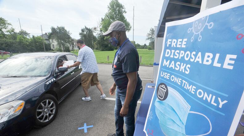 John Payne, left and Gilbert Ghand, with Dayton & Montgomery Public Health, help to giveaway free disposable mask Monday at the Mount Olive Baptist Church. MARSHALL GORBY\STAF