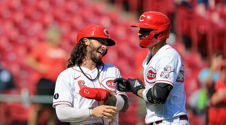 Cincinnati Reds' Nick Castellanos, right, celebrates hitting a three-run home run with Jonathan India during the sixth inning of a baseball game against the Pittsburgh Pirates in Cincinnati, Monday, Sept. 27, 2021. (AP Photo/Aaron Doster)