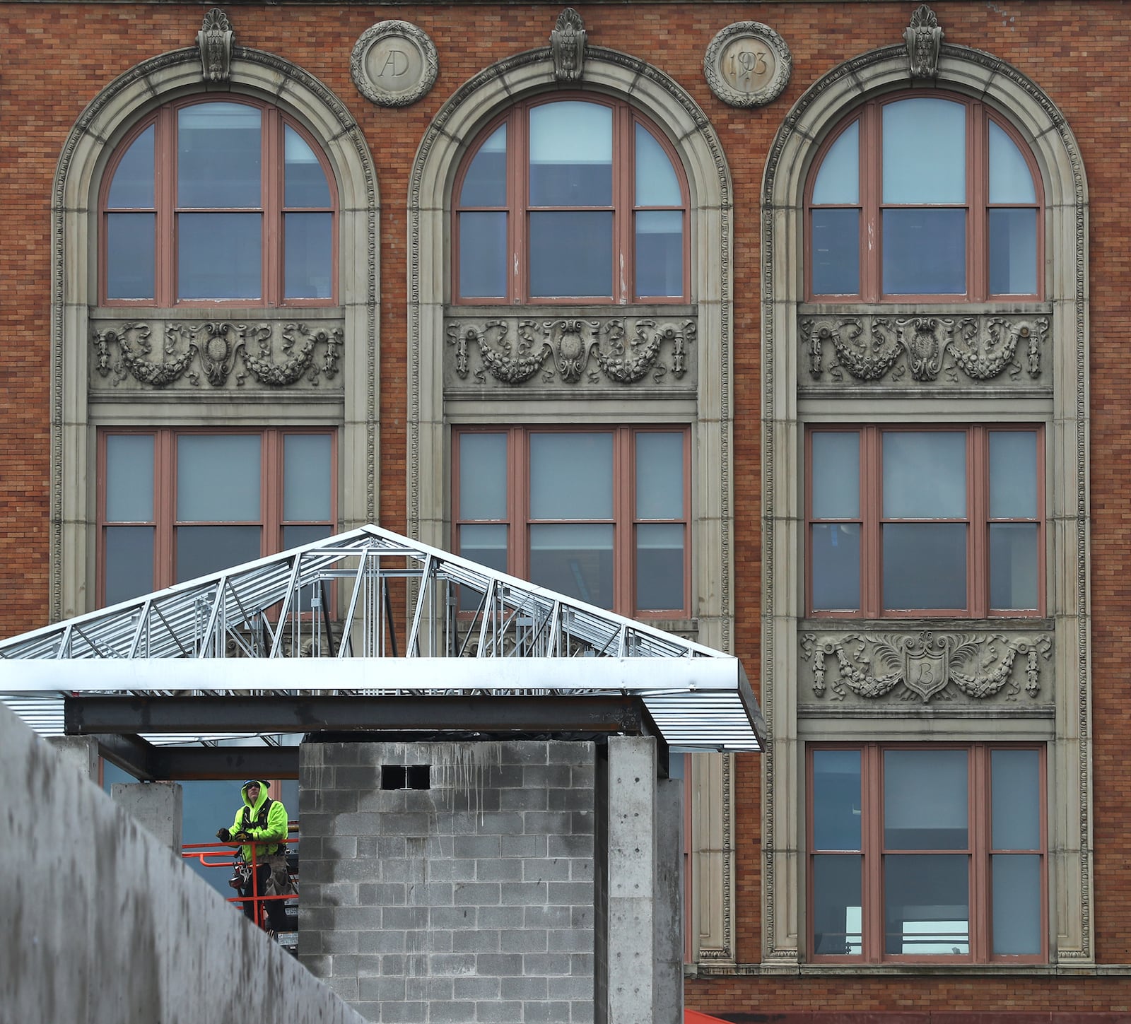 The Bushnell Building provides a background for a construction worker building a small roof on a corner of the new parking garage being built in downtown Springfield Tuesday. BILL LACKEY/STAFF