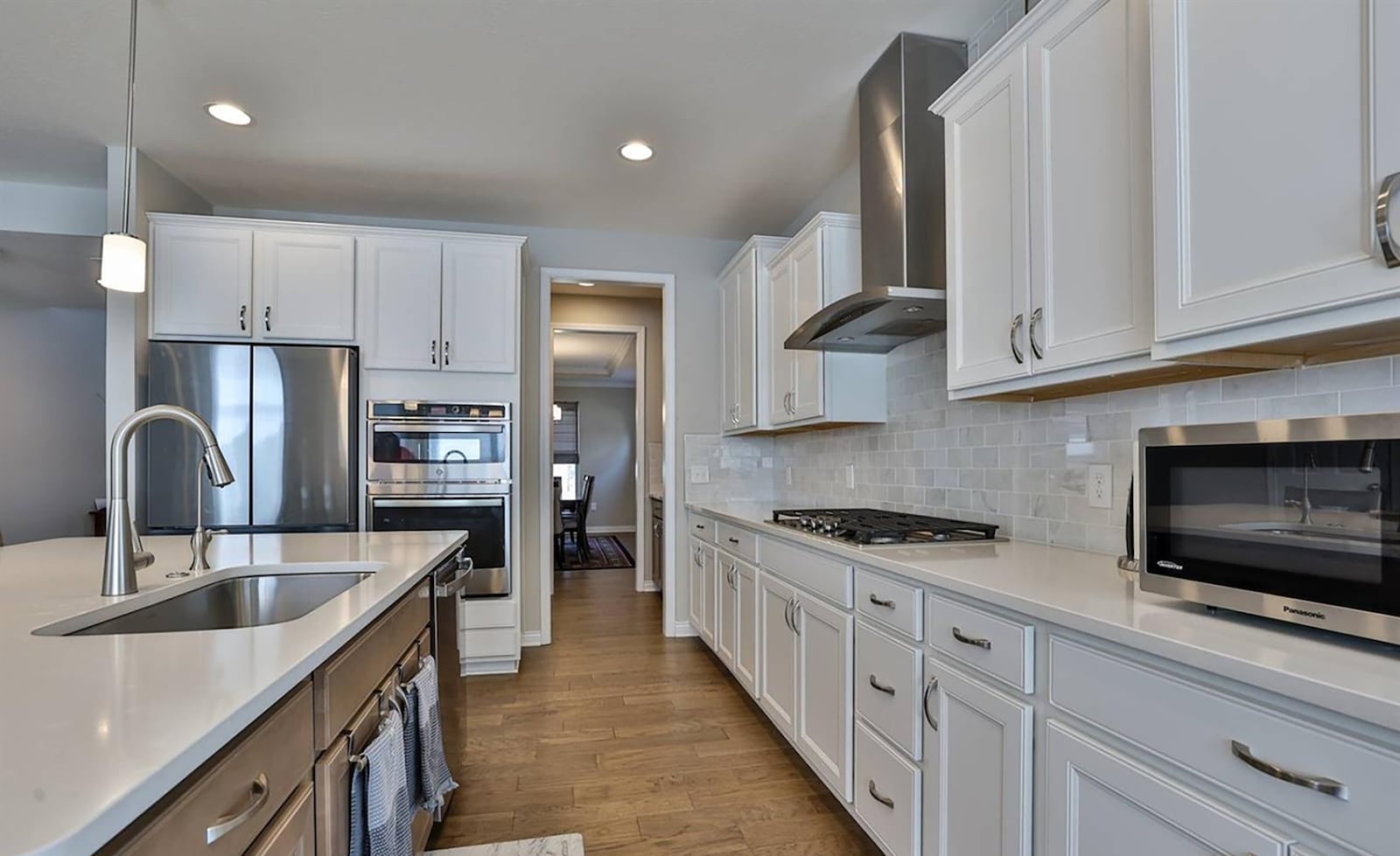 The kitchen has hardwood plank flooring, an island and stainless appliances. There is also a butler's pantry.