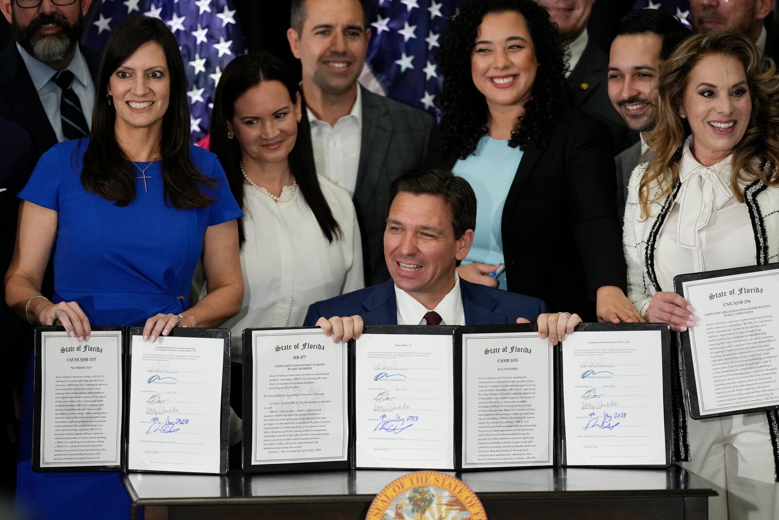 FILE - Florida Governor Ron DeSantis, seated, and other elected, state, and local officials pose with a group of education-related bills after DeSantis signed them into law at a press conference in Miami, Tuesday, May 9, 2023. (AP Photo/Rebecca Blackwell, File)
