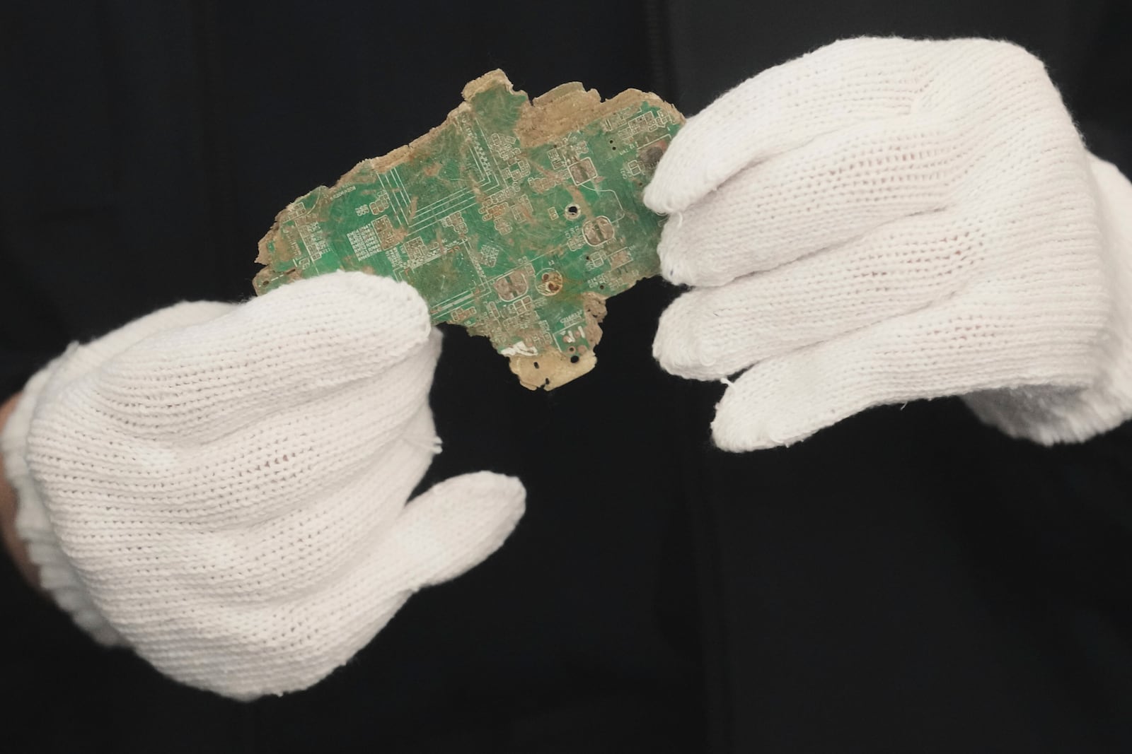 A Thai official shows a sample of illegally imported electronic waste from the United States which they said they seized at Bangkok Port during a press conference in Bangkok, Thailand, Wednesday, May 14, 2025. (AP Photo/Sakchai Lalit)