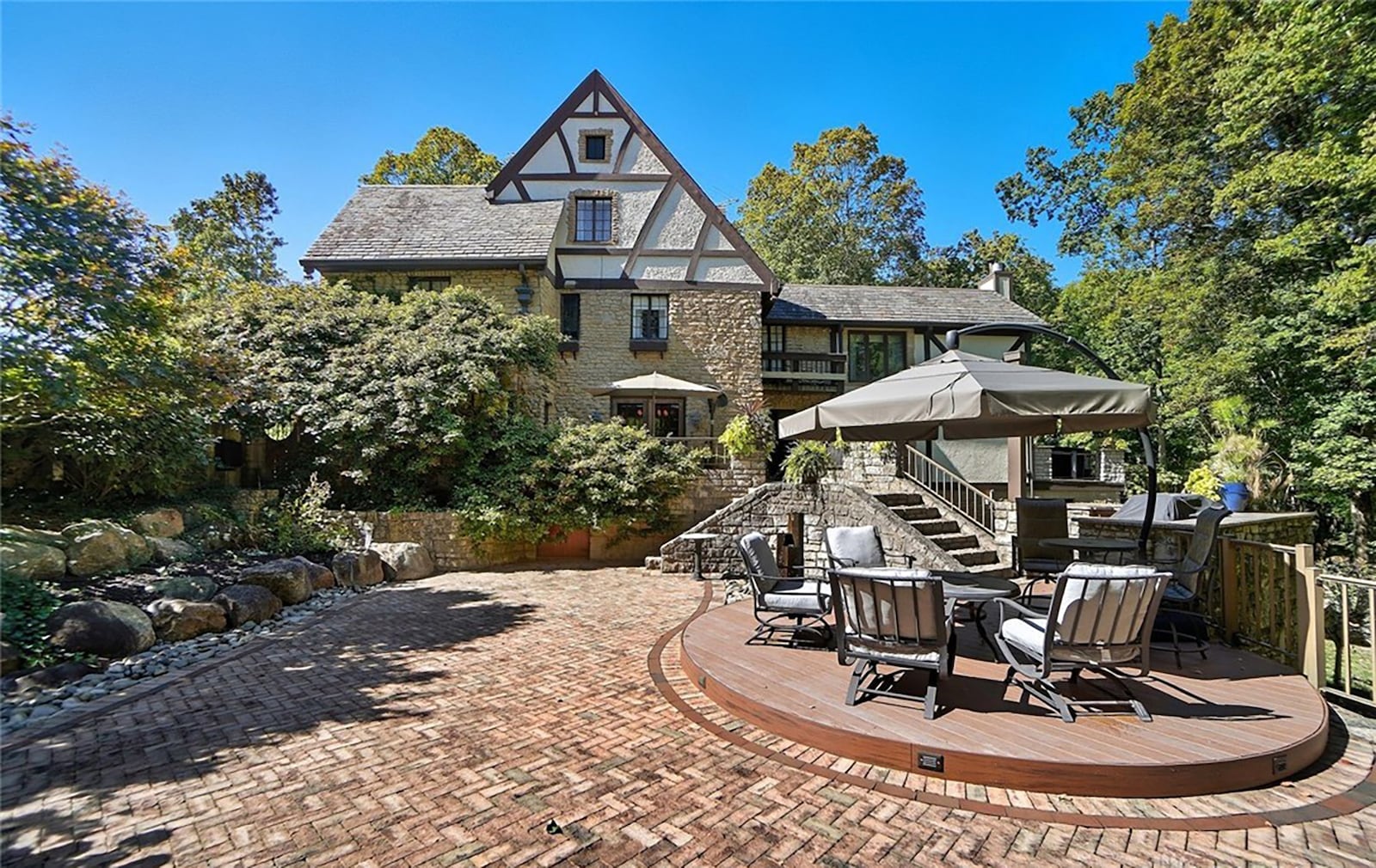 The back of the home features a brick paver patio, stone retaining walls and steps, a firepit, hot tub and separate deck with railings. CONTRIBUTED