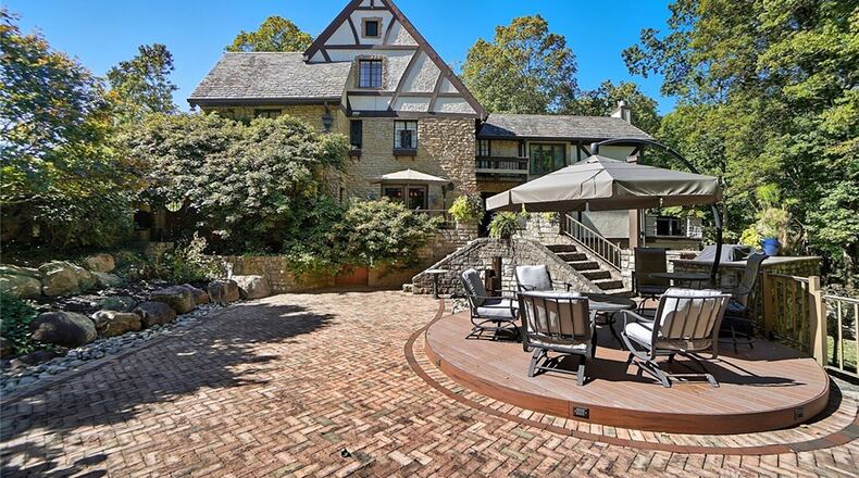 The back of the home features a brick paver patio, stone retaining walls and steps, a firepit, hot tub and separate deck with railings. CONTRIBUTED