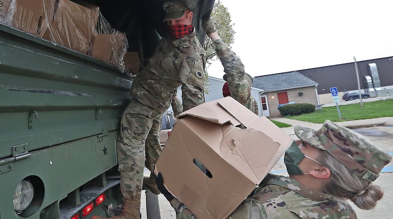 Ohio Army National Guard Spc Logan Wilson hands off a box of food to Sgt Makayla Scharber as they deliver food from the Second Harvest Food Bank to hungry residents in New Carlisle Friday. BILL LACKEY/STAFF
