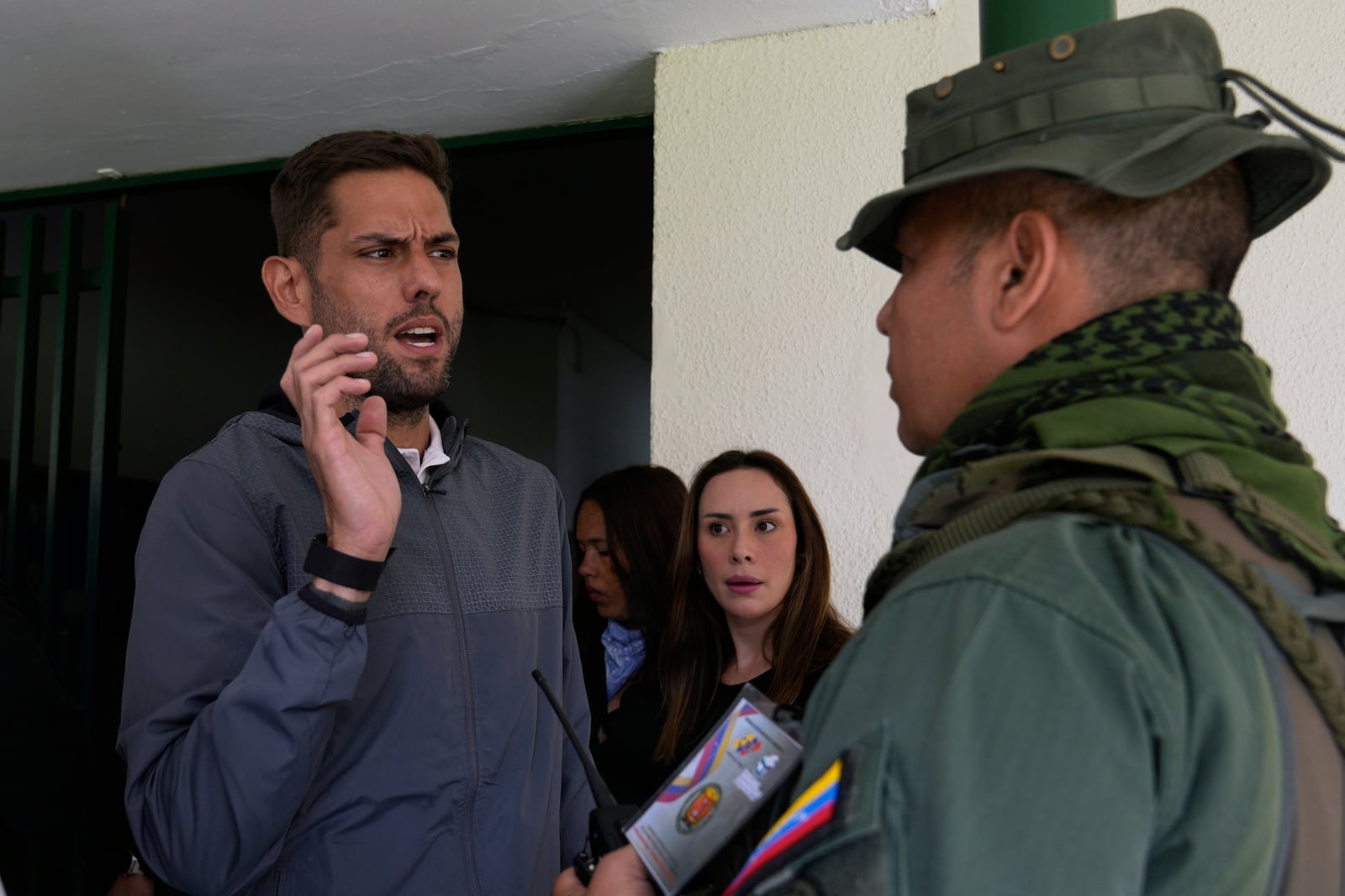 Juan Requesens, former opposition lawmaker and candidate for governor of Miranda state, talks to a National Guard officer upon arriving at a polling station during legislative and local elections in Caracas, Venezuela, Sunday, May 25, 2025. (AP Photo/Ariana Cubillos)