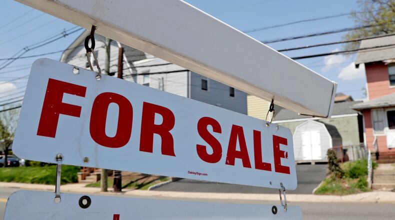 FILE - A "for sale" sign hangs from a post outside of a vacant business building in Belleville, N.J., Thursday, May 3, 2018.  The Federal Reserve on Wednesday, July 27,  raised its benchmark interest rate by a hefty three-quarters of a point for a second straight time in its most aggressive drive in three decades to tame high inflation.  By raising borrowing rates, the Fed makes it costlier to take out a mortgage or an auto or business loan.(AP Photo/Julio Cortez, File)