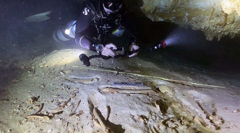 In this handout photo provided by the National Institute of Anthropology and History, underwater archaeologist Octavio del Río takes photos of the remains of a prehistoric human skeleton discovered inside the flooded cave system in Actun, near Tulum, Mexico, Nov. 18, 2025. (Eugenio Acevez/National Institute of Anthropology and History via AP)