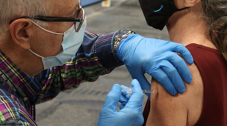Dave Torsell gives a woman the Johnson and Johnson vaccine injection at a clinic in Urbana. BILL LACKEY/STAFF