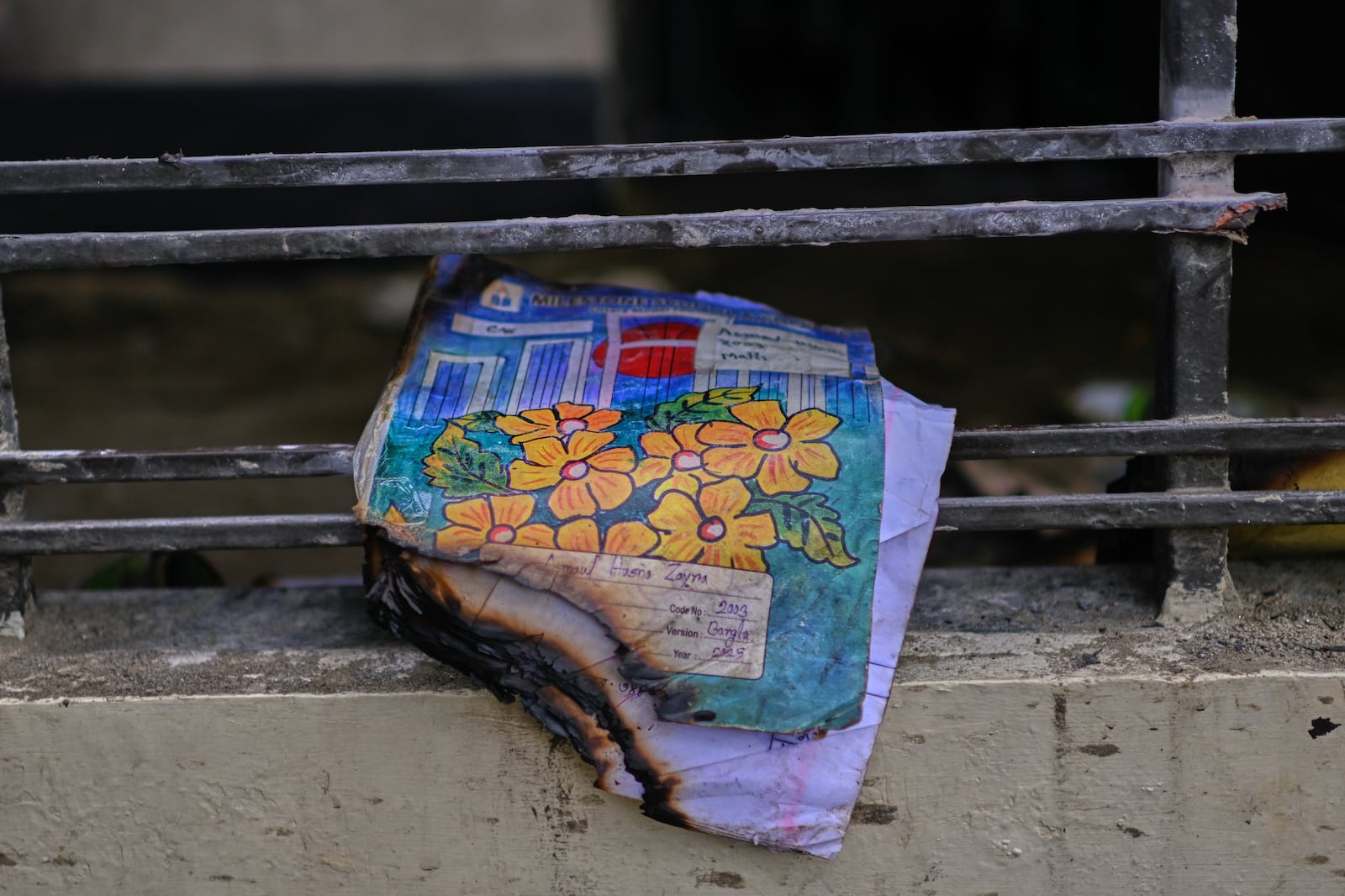 A burnt book of a student is seen at the window of a school after a Bangladesh air force training jet crashed into it Monday in Dhaka, Bangladesh, Tuesday, July 22, 2025. (AP Photo/Mahmud Hossain Opu)