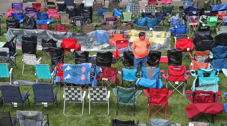 Gary Haggy stands in a sea of lawn chairs at the Veteran's Park Amphitheater Friday, June 9, 2022 as he tries to find the two chairs that he set-up earlier. The entire lawn at the amphitheater was filled with chairs and blankets as people saved their spots for the Summer Arts Festival performance of Resurrection: A Journey Tribute. BILL LACKEY/STAFF