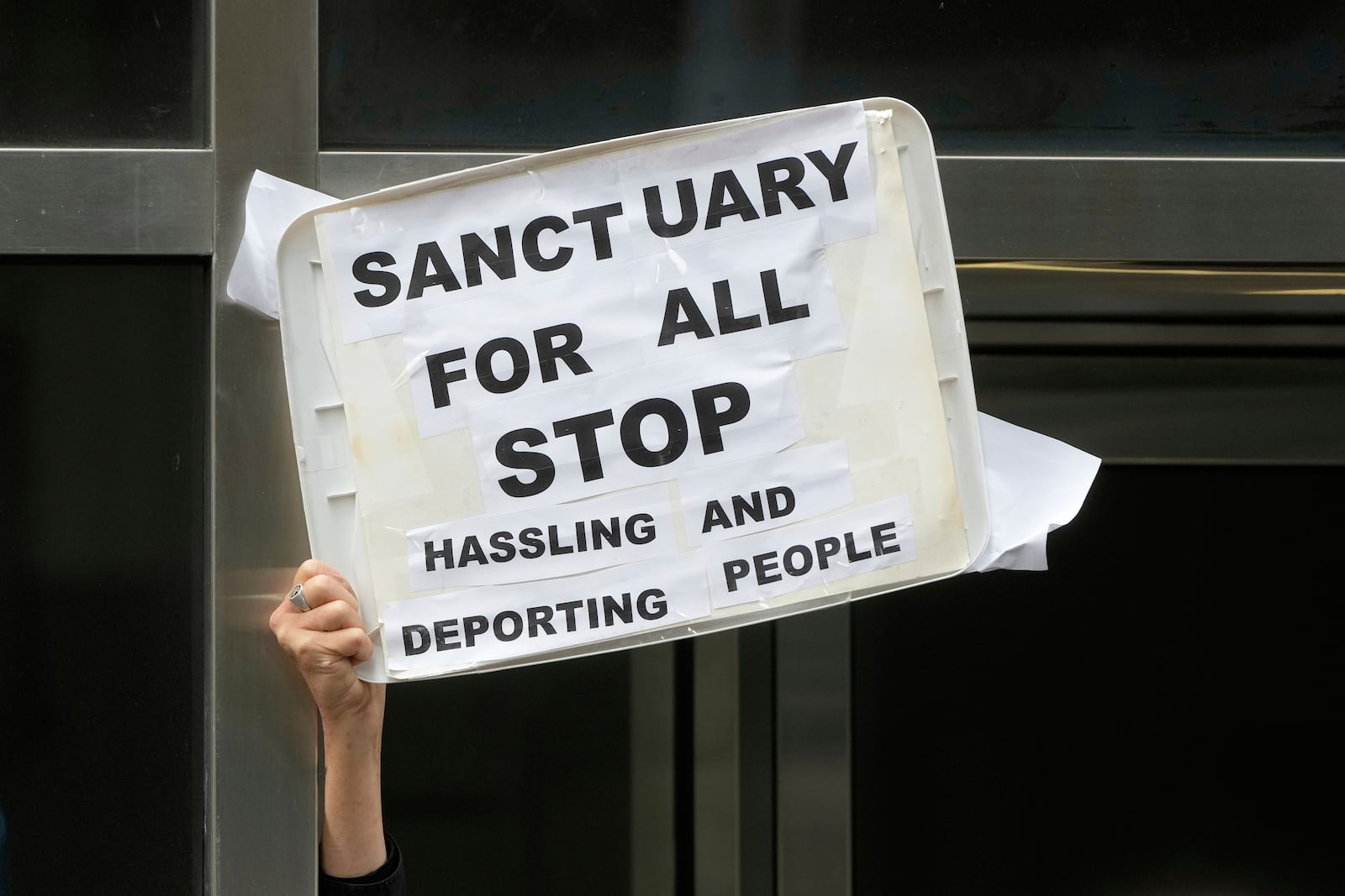 A person holds up a sign during a news conference and rally by immigrant justice organizations and advocates protesting ICE arrests in San Francisco, Wednesday, May 28, 2025. (AP Photo/Jeff Chiu)