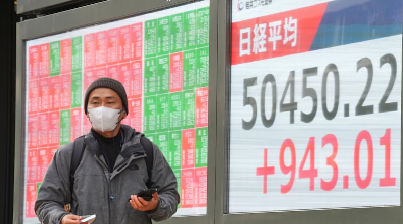 A person walks in front of an electronic stock board showing Japan's Nikkei index at a securities firm Monday, Dec. 22, 2025, in Tokyo. (AP Photo/Eugene Hoshiko)