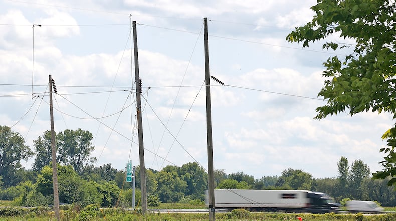Traffic speeds by on Interstate 70 Monday, July 31, 2023. The interstate was closed for several hours Saturday after a helicopter accidentally cut the power lines, pictured in the foreground, that stretch over the roadway. BILL LACKEY/STAFF