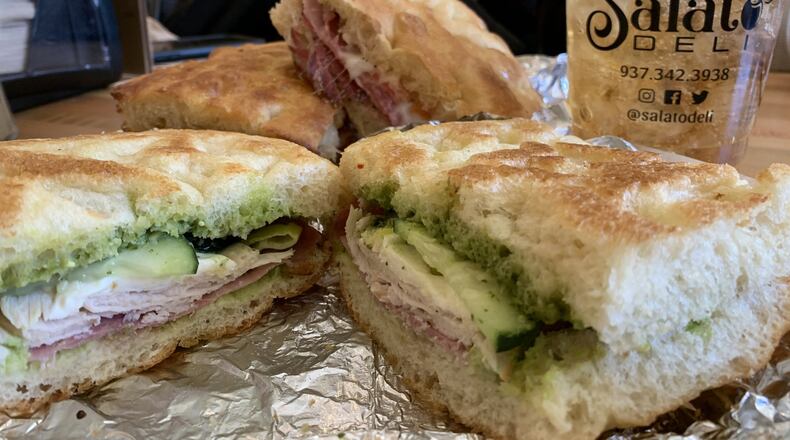 The Boss ($8), a blend of Italy and America made with turkey, Genoa salami, fresh mozzarella, fresh house made pesto, balsamic vinegar, cucumber, avocado, and pepperoncini on that special focaccia blessed with olive oil that is made in-house daily from scratch. The Roamin’ Italian ($8) is pictured in the background. CONTRIBUTED/ALEXIS LARSEN