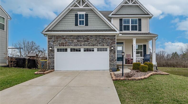 The front of the home has stone accents around the two car attached garage and sits next to an oversized pond with fountain.