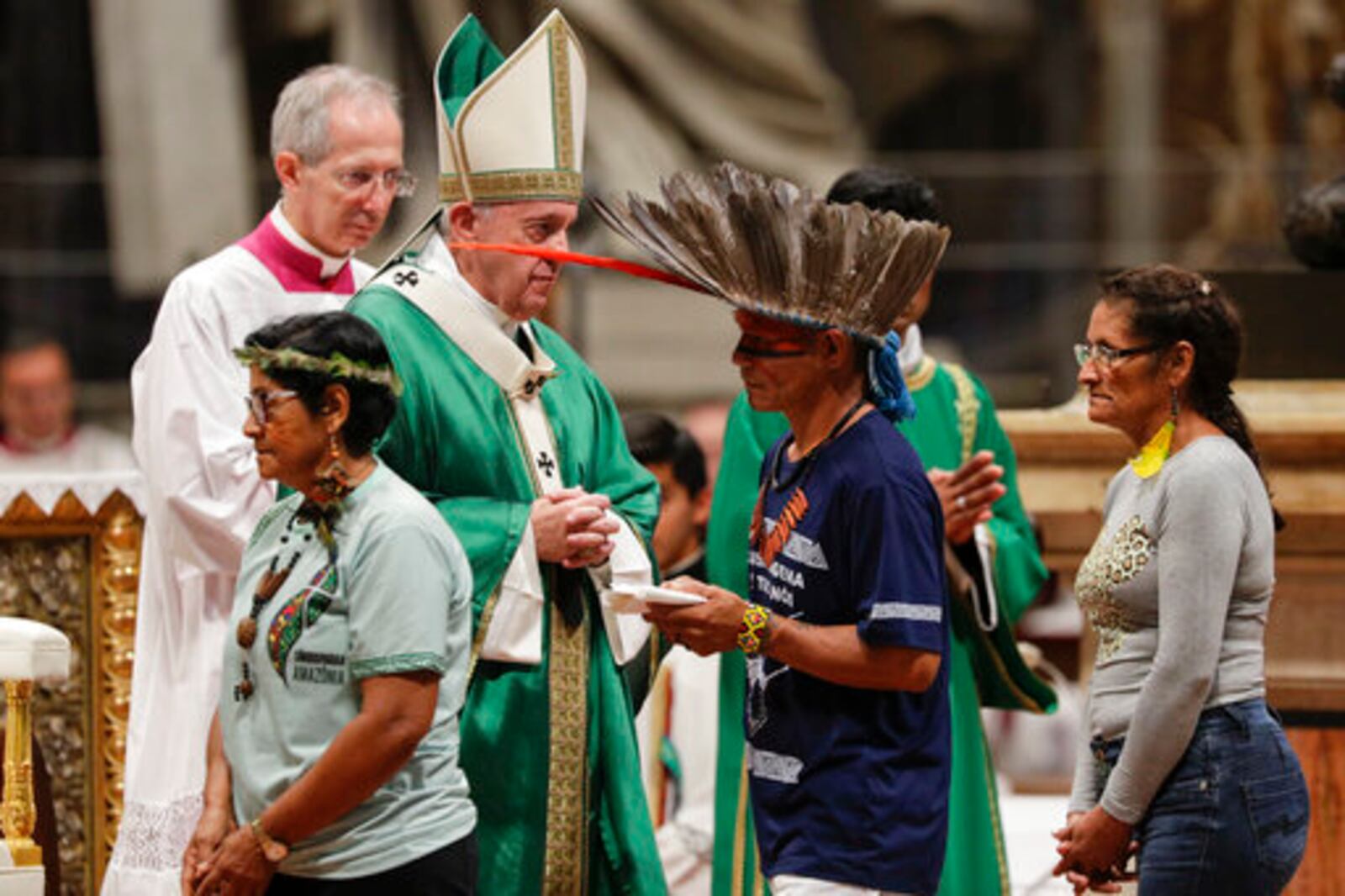 FILE - Indigenous peoples, some with their faces painted and wearing feathered headdresses, walk past Pope Francis as he celebrates an opening Mass for the Amazon synod, in St. Peter's Basilica, at the Vatican, Sunday, Oct. 6, 2019. (AP Photo/Andrew Medichini, file)