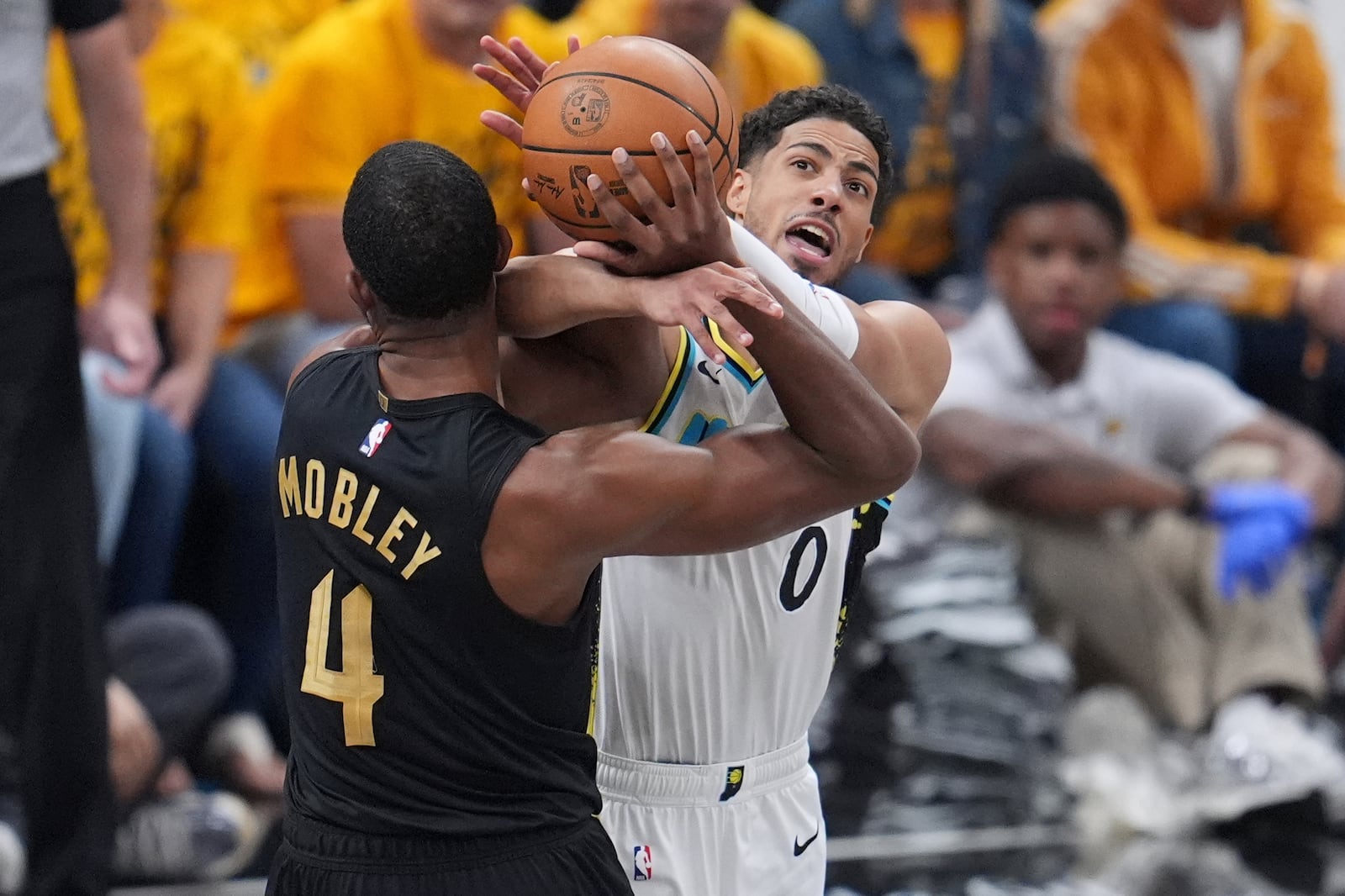 Indiana Pacers guard Tyrese Haliburton (0) and Cleveland Cavaliers center Evan Mobley (4) battle for the ball during the first half of Game 3 in the Eastern Conference semifinals of the NBA basketball playoffs in Indianapolis, Friday, May 9, 2025. (AP Photo/Michael Conroy)