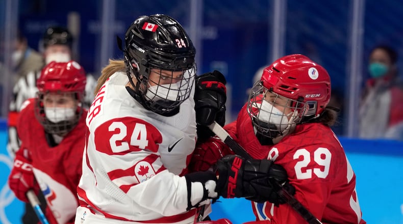 FILE - Canada's Natalie Spooner (24) and Russian Olympic Committee's Alexandra Vafina (29) wear COVID masks during a preliminary round women's hockey game at the 2022 Winter Olympics, Feb. 7, 2022, in Beijing. (AP Photo/Petr David Josek, File)