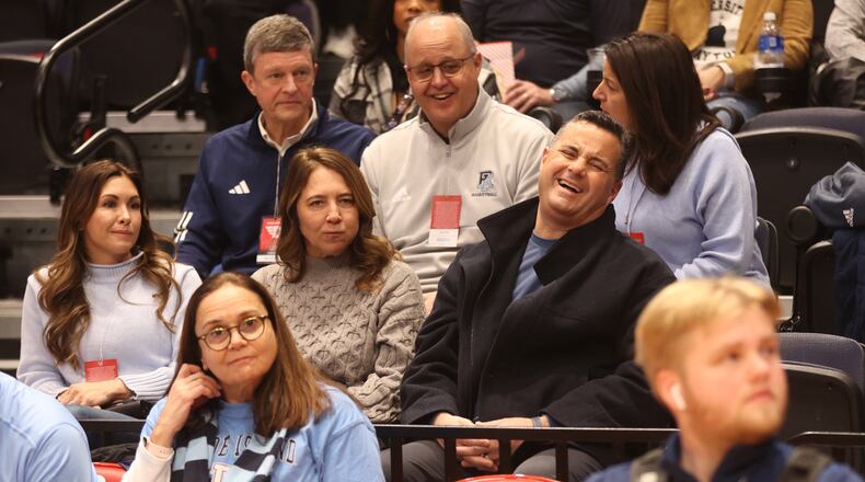 Xavier coach Sean Miller laughs before Rhode Island's game against Dayton on Saturday, Jan. 20, 2024, at UD Arena. Miller came to watch his brother Archie Miller coach. At left is Morgan Miller, Archie's wife, and Amy Miller, Sean's wife, is at center. David Jablonski/Staff