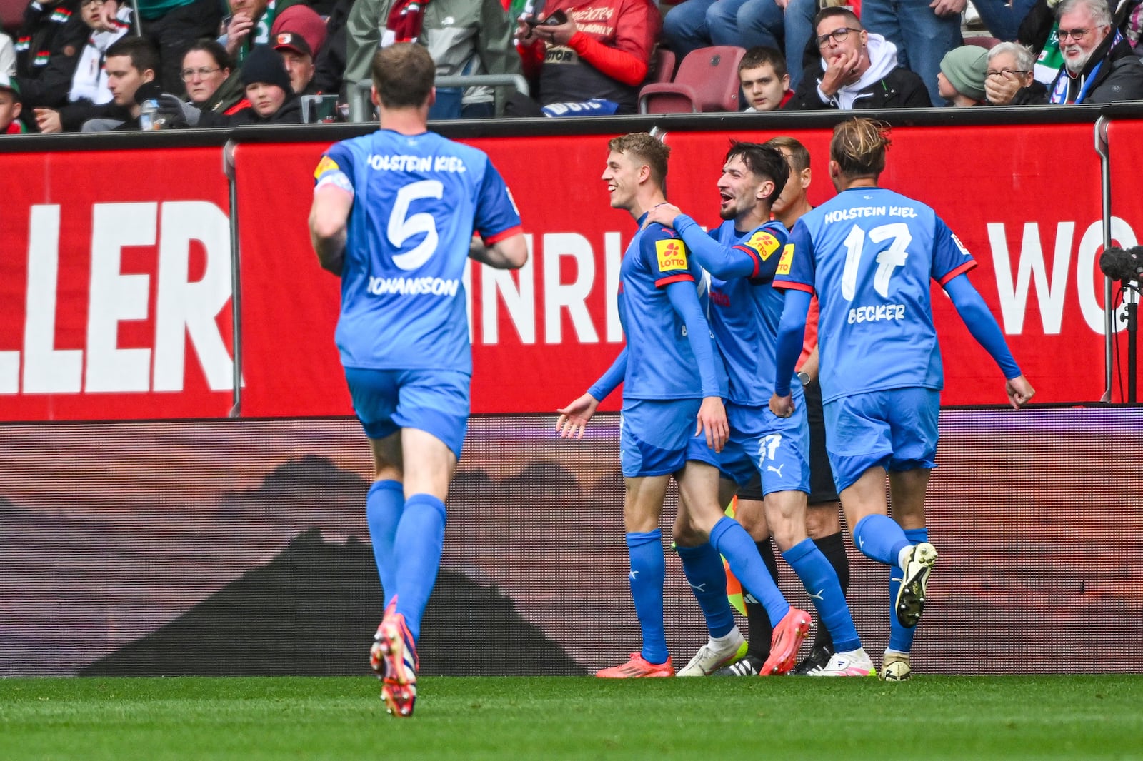Kiel's Ivan Nekic, second left, celebrates with his teammates after scoring against Augsburg during the German Bundesliga soccer match between FC Augsburg and Holstein Kiel at the WWK-Arena in Augsburg, Germany, Sunday, May 4, 2025. (Armin Weigel/dpa via AP)