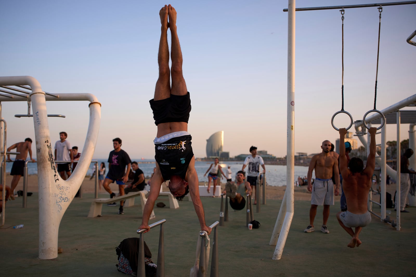 People work out in an open-air gym next to the beach in Barcelona, Spain, Tuesday, June 25, 2025. (AP Photo/Emilio Morenatti)