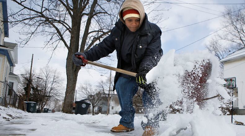Corey Williams shovels the sidewalk in front of his home on E. Second St. in Dayton. TY GREENLEES / STAFF