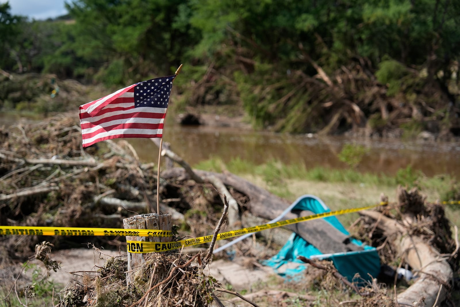 An American flag is placed on a stump in Kerrville, Texas on Tuesday, July 8, 2025. (AP Photo/Ashley Landis)