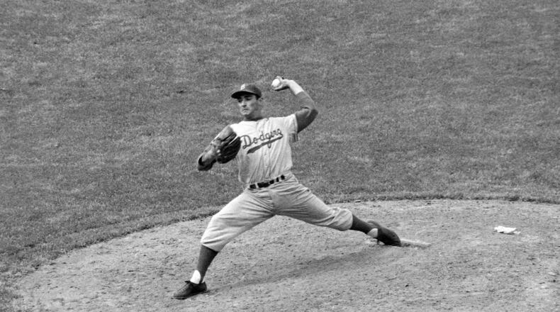Brooklyn Dodgers southpaw Sandy Koufax, who ended his bonus tenure the day before, pitches against the Chicago Cubs in the eighth inning of a baseball game, Thursday, May 16, 1957, in Chicago. On Monday, March 14, 2022, the Los Angeles Dodgers announced that Koufax is joining fellow Hall of Famer Jackie Robinson with a bronze statue of his own at Dodger Stadium, with an unveiling planned for June 18, 2022, before the team hosts Cleveland. (AP Photo/Harry Hall, File)