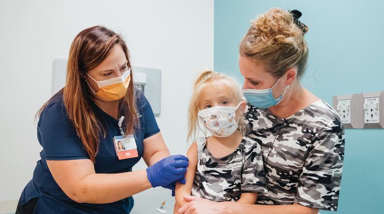 Delaney Bowser (middle) sits with her mom, Kristen Bowser, as Delaney prepares to get her first COVID-19 vaccine at a recent vaccine clinic held at Dayton Children's Hospital. CONTRIBUTED