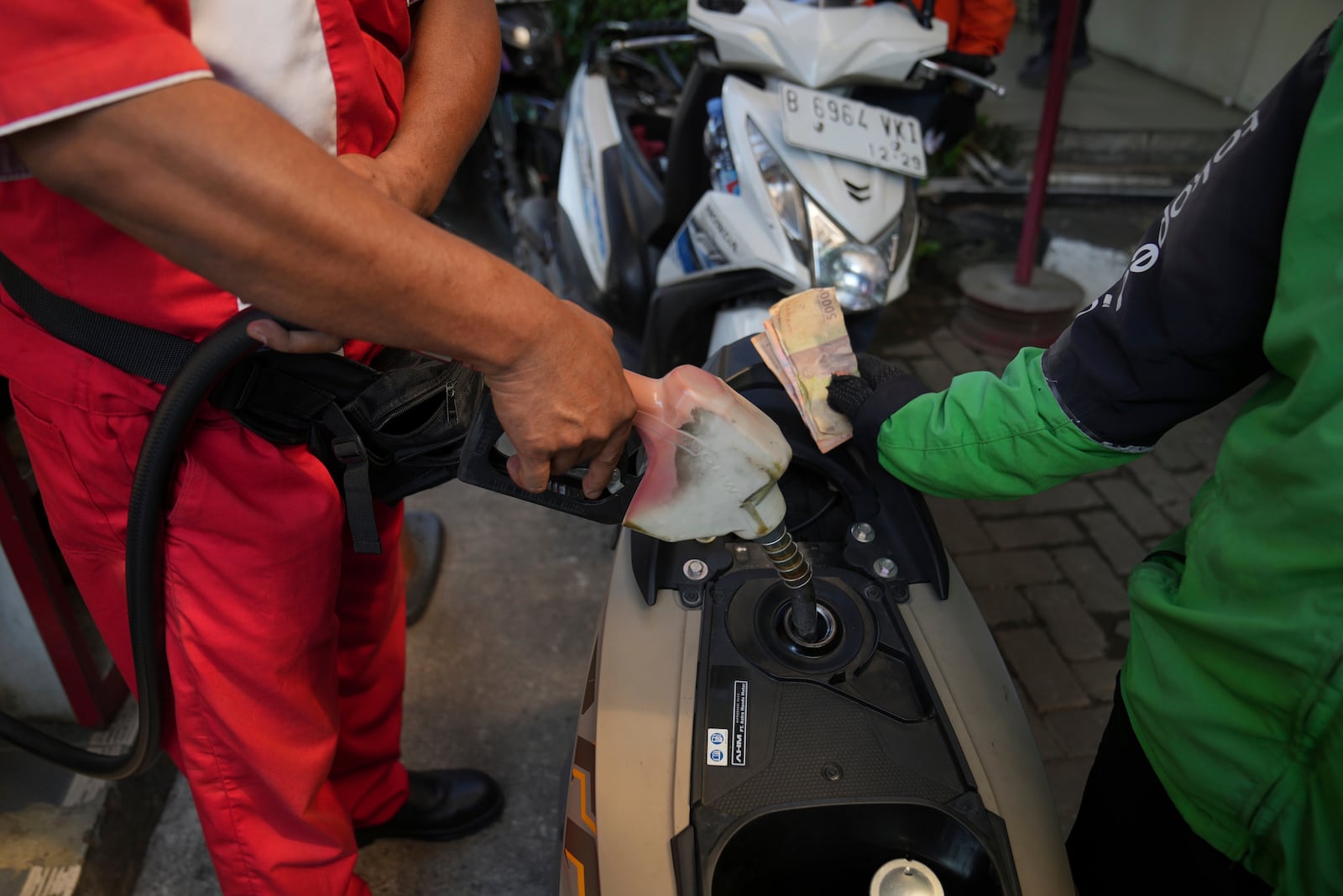 An employee fills up the tank of a customer's motorbike at a gas station in Jakarta, Indonesia, Monday, May 5, 2025. (AP Photo/Tatan Syuflana)