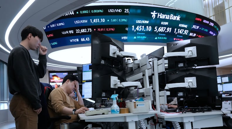 Currency traders work near a screen showing the Korea Composite Stock Price Index (KOSPI), top center, and the foreign exchange rate between U.S. dollar and South Korean won, top center left, at the foreign exchange dealing room of the Hana Bank headquarters in Seoul, South Korea, Friday, Feb. 20, 2026. (AP Photo/Ahn Young-joon)