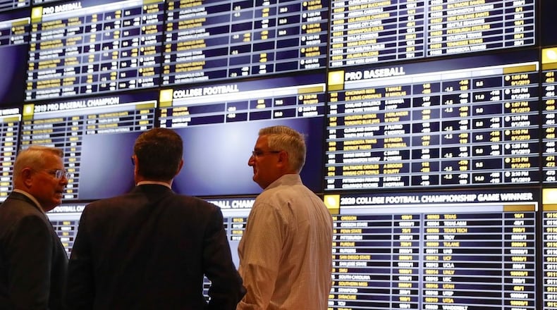 Indiana Gov. Eric Holcomb (right) talks with Ron Baumann (center), general manager of Indiana Grand Racing & Casino, and Shelbyville Mayor Tom Debaun in the sports betting area at the Indiana Grand Racing & Casino in Shelbyville, Ind., on Sept. 1, 2019. The Ohio Senate on Wednesday approved legislation to legalize sports betting in Ohio along with a bill to allow college athletes to earn money based on the use of their names, images and likenesses. Michael Conroy / ASSOCIATED PRESS