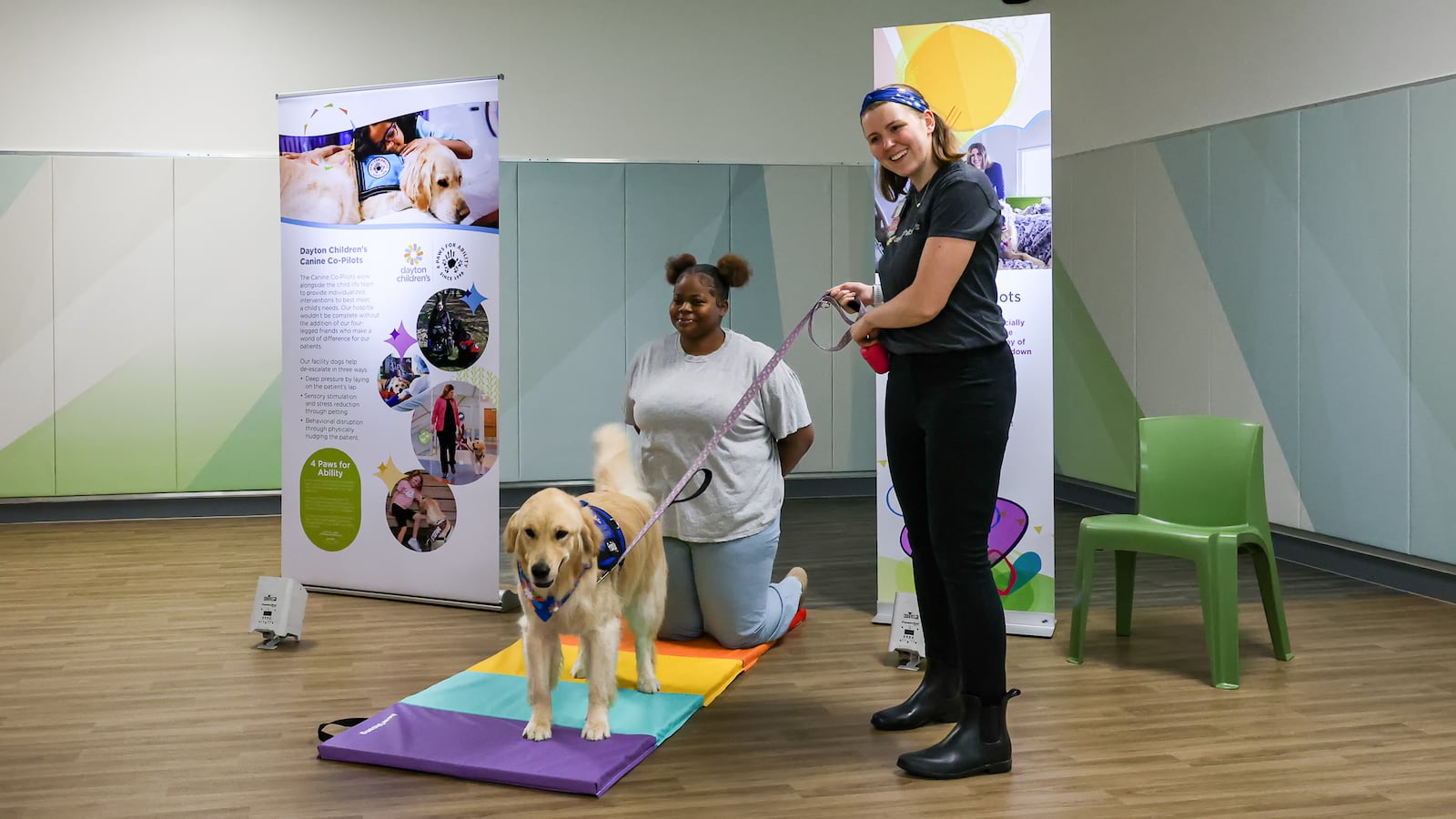 Taylor Rieck (right) laughs while answering a question during a tour of Mathile Center for Mental Health and Wellness on Monday. Rieck is the primary handler of Piper, a service dog who comforts patients. Marissa White (center), a volunteer, portrays a patient. BRYANT BILLING / STAFF