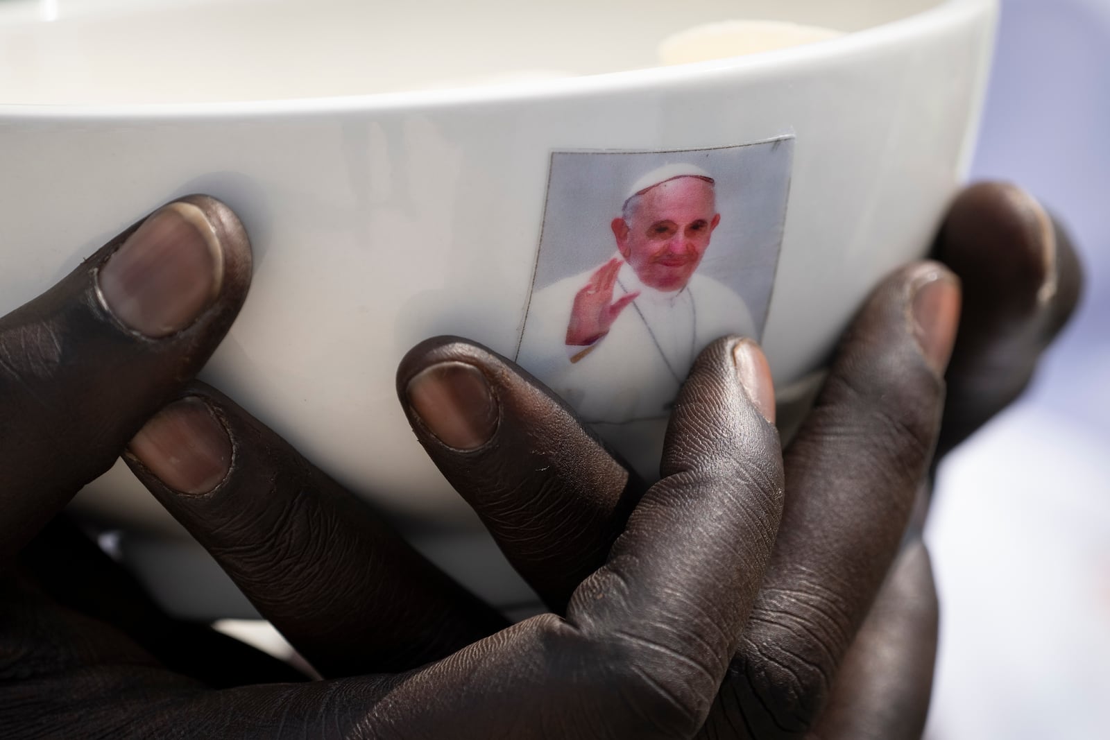 FILE - A priest holds a sacrament bowl showing a photograph of Pope Francis during a Holy Mass at the John Garang Mausoleum in Juba, South Sudan, Feb. 5, 2023. (AP Photo/Ben Curtis, File)