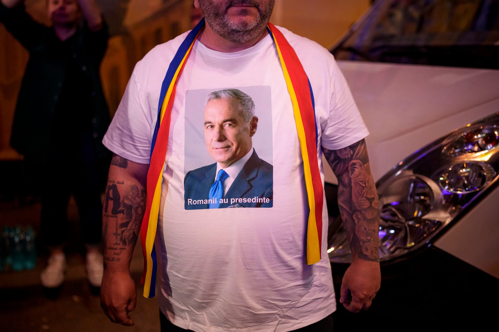 A man wears a t-shirt showing Calin Georgescu, winner of the first round of last year's voided election outside the headquarters of presidential candidate George Simion, after polls closed during the first round of the country's presidential election redo in Bucharest, Romania, Sunday, May 4, 2025. (AP Photo/Andreea Alexandru)