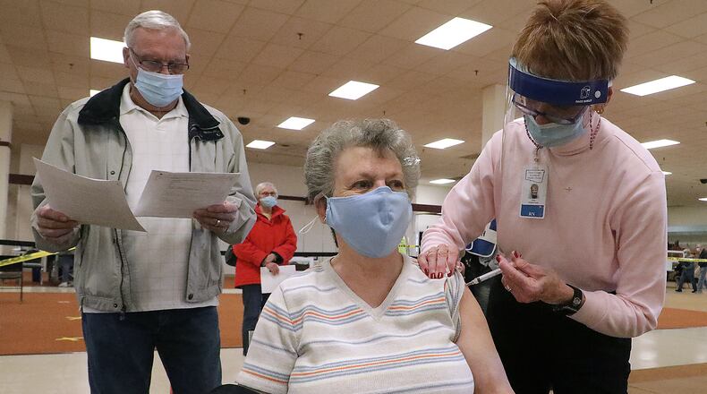 Janet Bare gets a COVID vaccine shot from Judy Livingston, a RN with the Clark County Combined Health District, on Jan. 20 as Janet's husband Ron waits his turn. BILL LACKEY/STAFF
