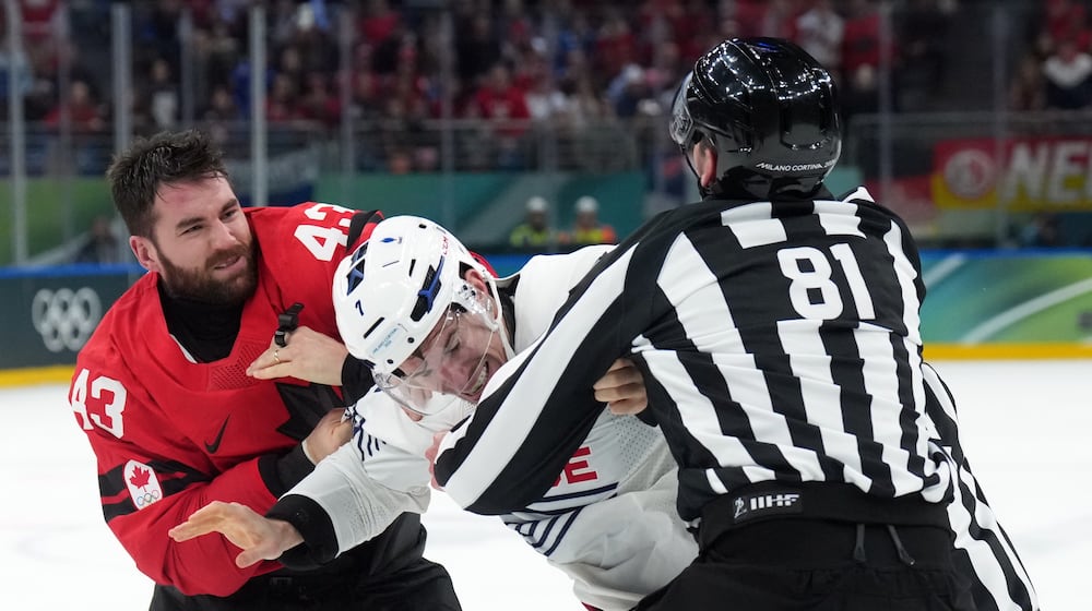 Canada's Tom Wilson (43) and France's Pierre Crinon, center, fight in the third period during a preliminary round game of men's ice hockey between Canada and France at the 2026 Winter Olympics, in Milan, Italy, Sunday, Feb. 15, 2026. (Nathan Denette/The Canadian Press via AP)