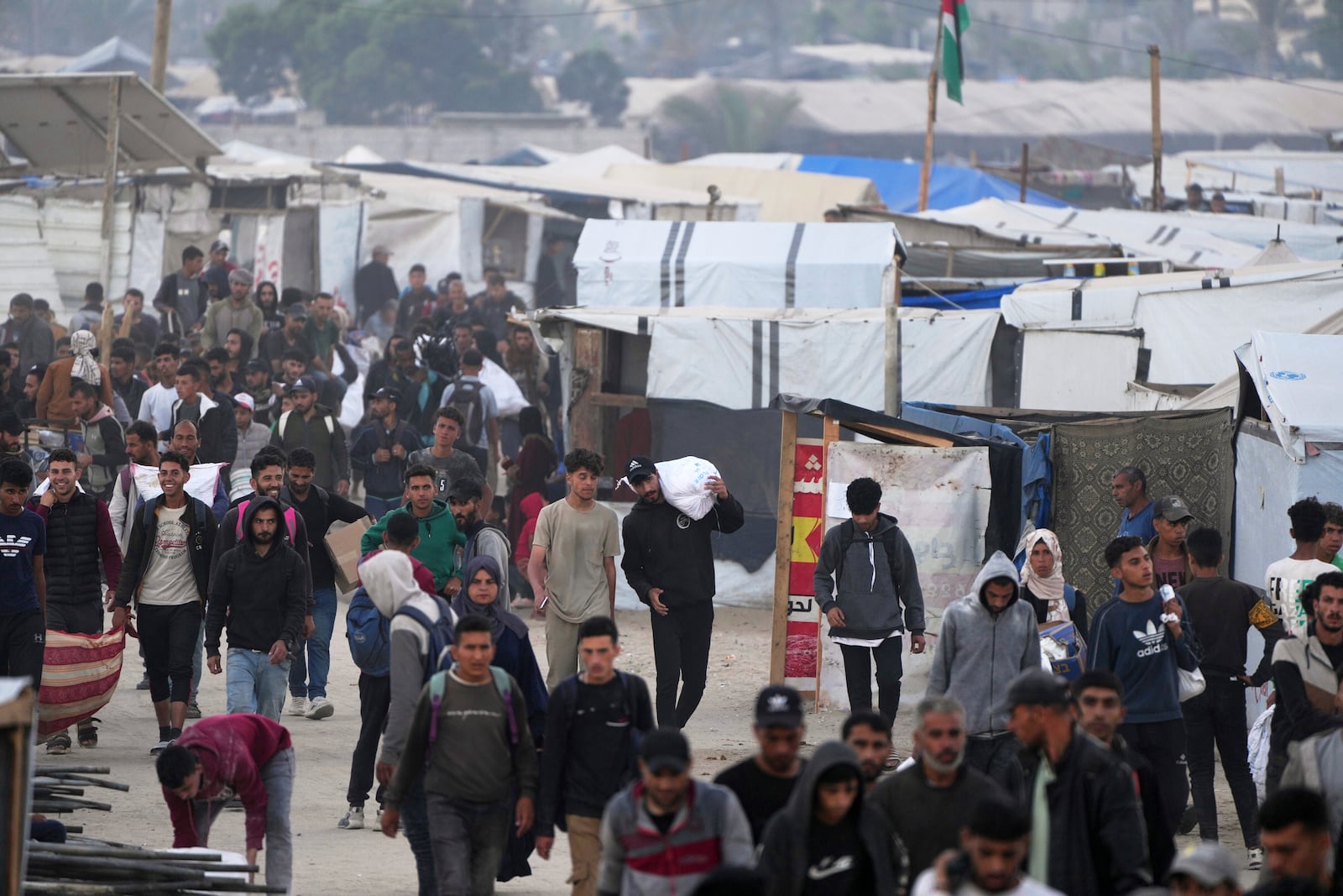 Palestinians carry bags filled with food and humanitarian aid provided by the Gaza Humanitarian Foundation, a U.S.-backed organization approved by Israel, in Khan Younis, southern Gaza Strip, on Tuesday, June 3, 2025. (AP Photo/Abdel Kareem Hana)