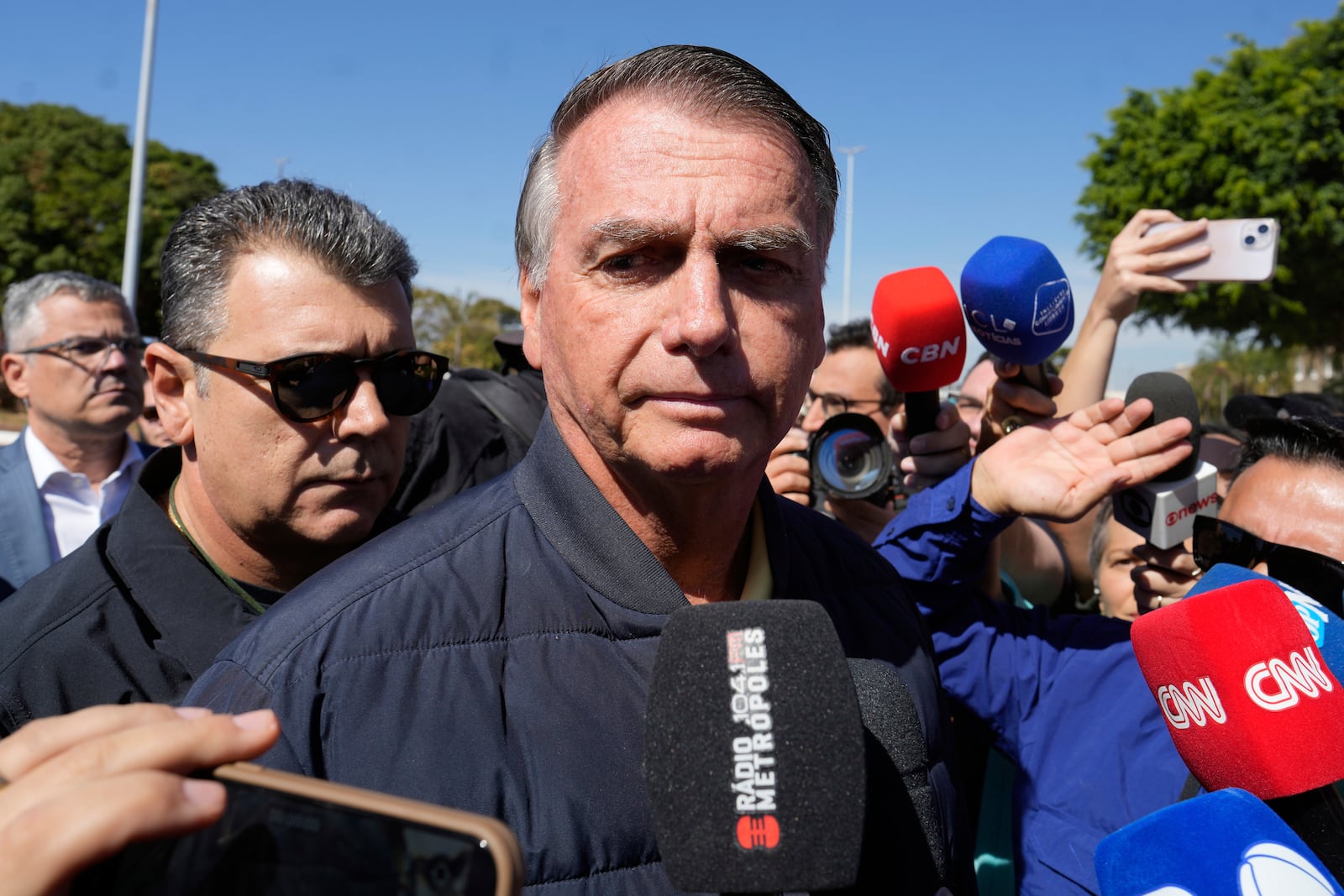 Brazil's former President Jair Bolsonaro speaks to the press outside the Secretariat of Penitentiary Administration where he arrived after the Supreme Court ordered him to be fitted with an electronic ankle monitor in Brasilia, Brazil, Friday, July 18, 2025. (AP Photo/Eraldo Peres)