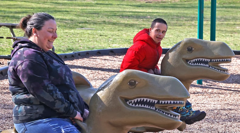 Valerie Rieben laughs as she rides the dinosaur playground toys in Veterans Park with her son, Thomas, on Tuesday, March 12, 2024. The only two on the playground, Valerie said they were just out enjoying the beautiful morning. BILL LACKEY/STAFF