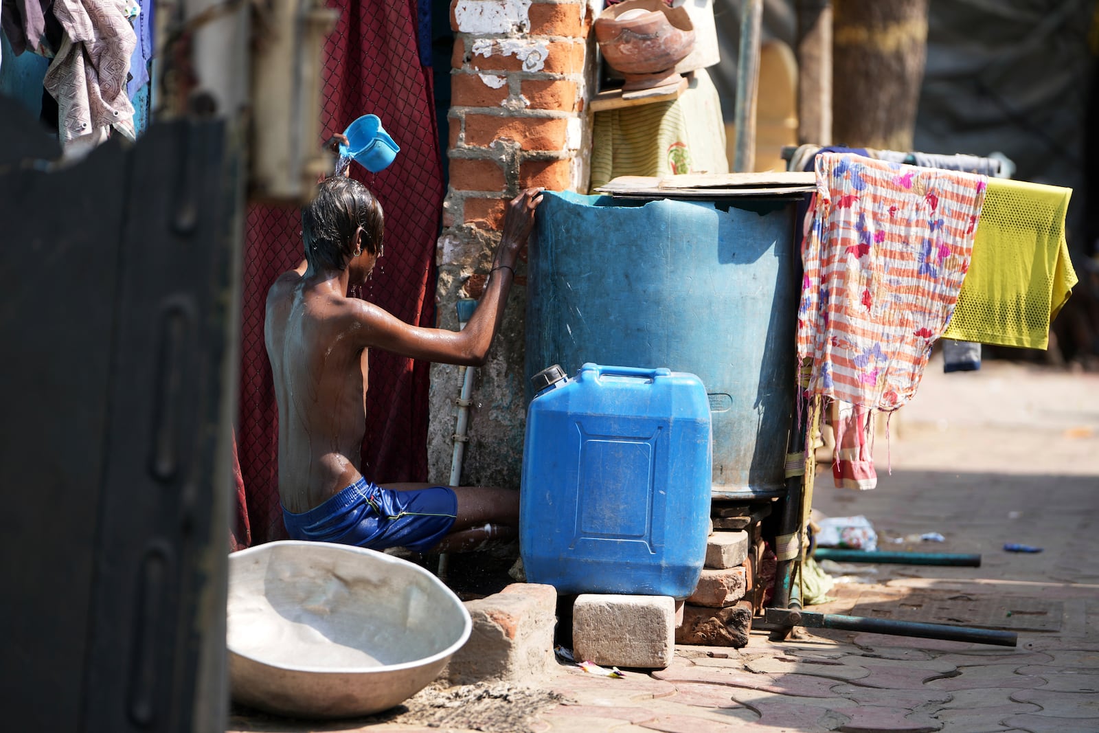 A youth bathes outside his home amid high temperatures in Ahmedabad, India, Wednesday, April 2, 2025. (AP Photo/Ajit Solanki)