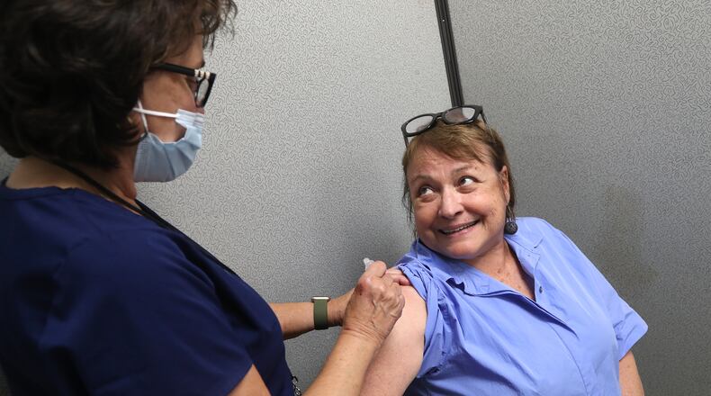 Gabriele Leventhal talks to Becky Schwaiger, an RN at the Clark County Combined Health District, as she gets a COVID vaccine shot in July. BILL LACKEY/STAFF
