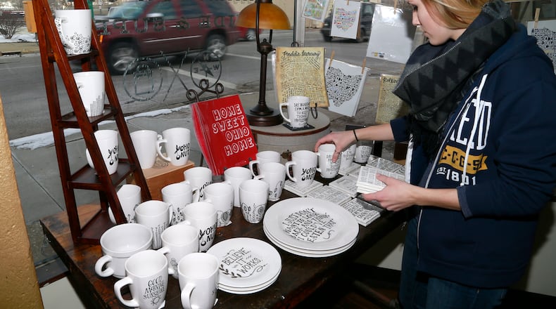 Kelcie Webster straightens up a display in the front window of Champion City Guide and Supply. Bill Lackey/Staff